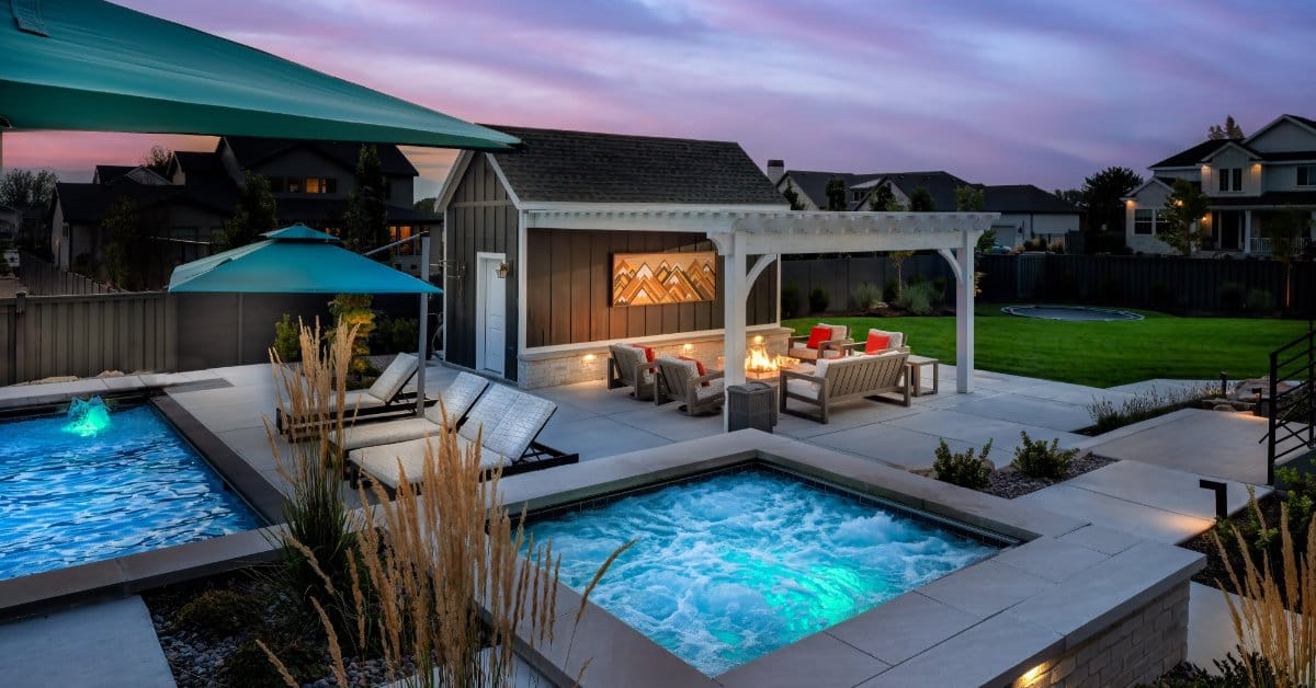 A corner view of an in-ground spa next to a small family pool. Behind the spa is a shed with an overhand and seats.