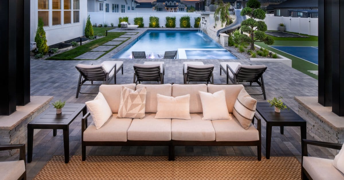 A modern poolside seating area with cushioned outdoor furniture, sleek patio design, and landscaped backyard oasis.