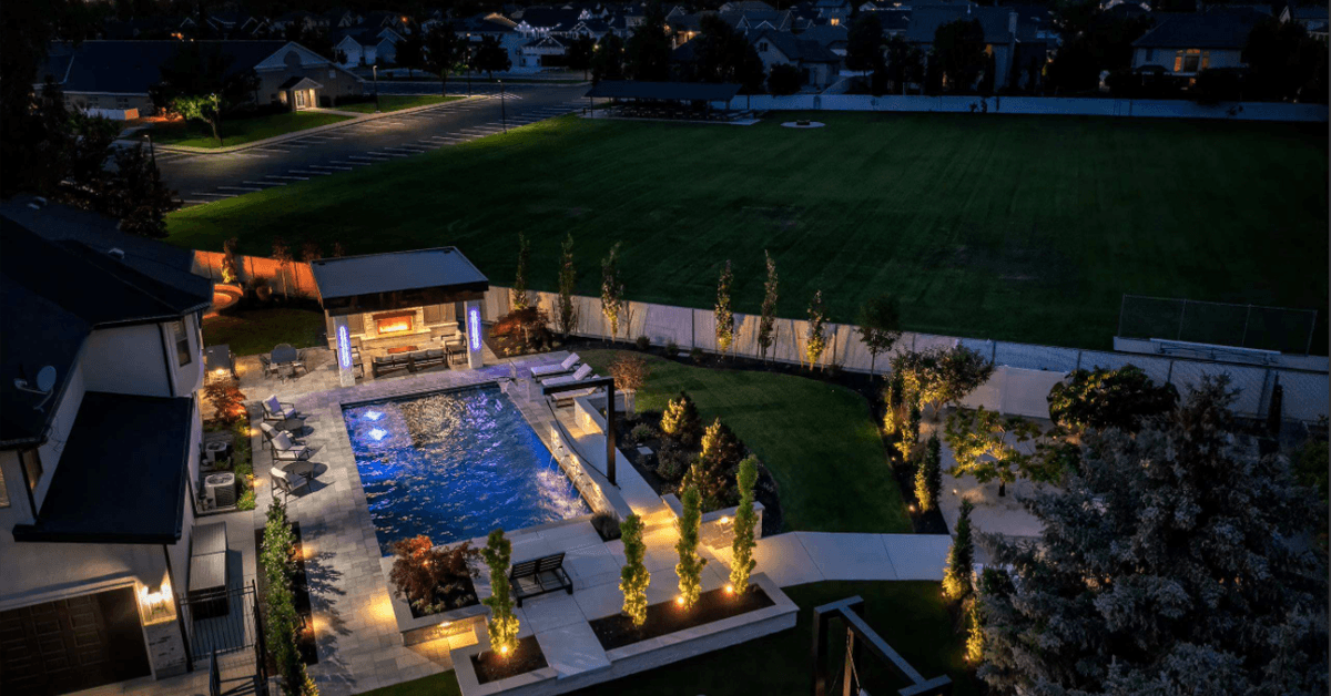 An aerial view of a Utah backyard. There is a rectangle pool and a pergola at the end with mountains in the background.