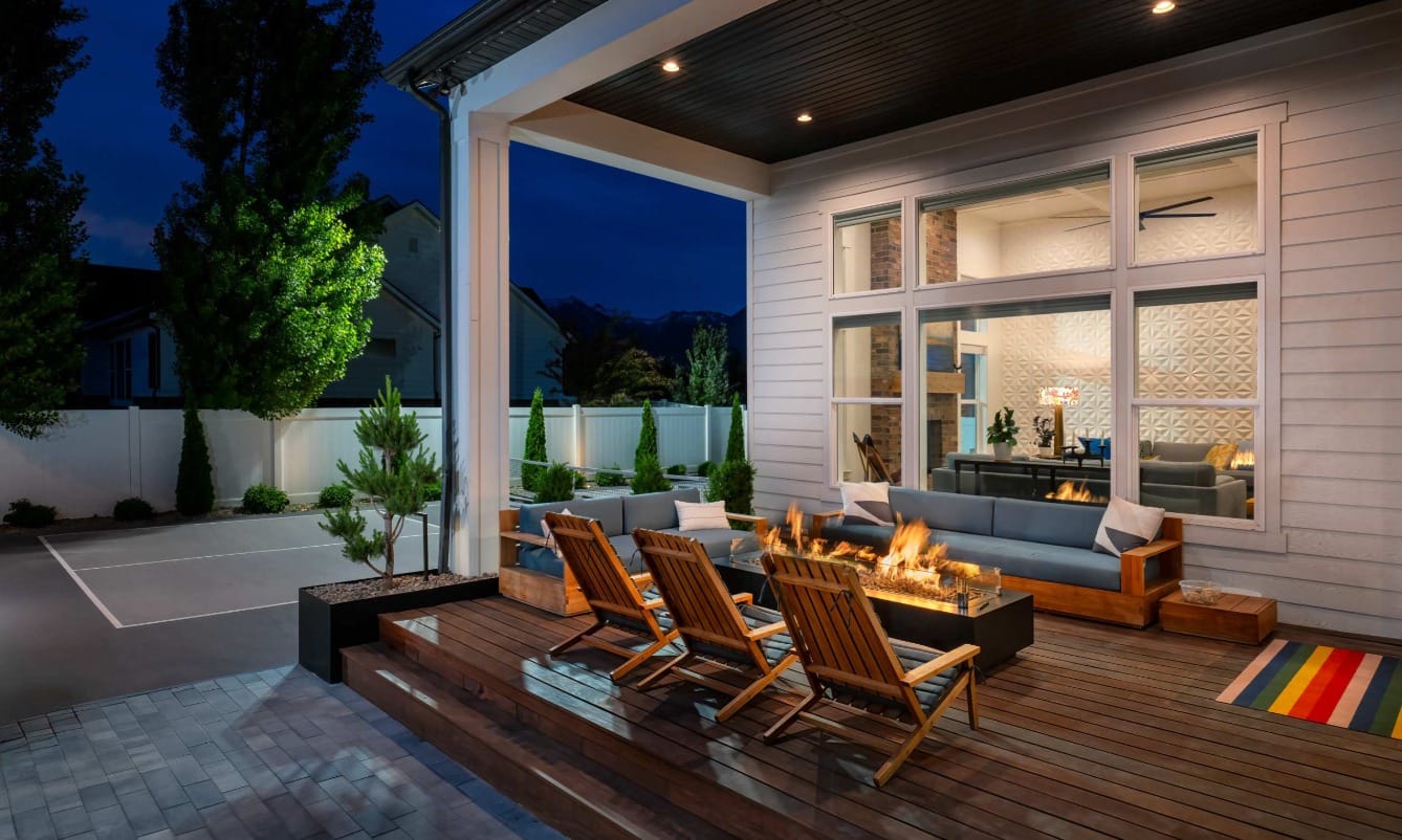 A custom designed deck area in a residential, Utah backyard. There are wooden deck chairs and a side yard tennis court.